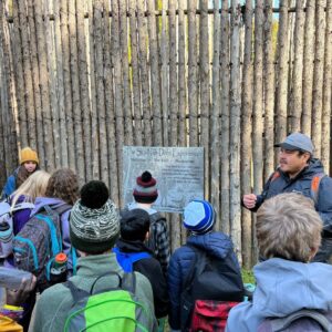 Group of youth engage with an educator outside of Ska-Nah-Doht Village